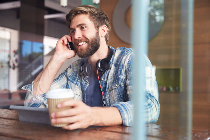 A man talking on a cell phone and holding coffee