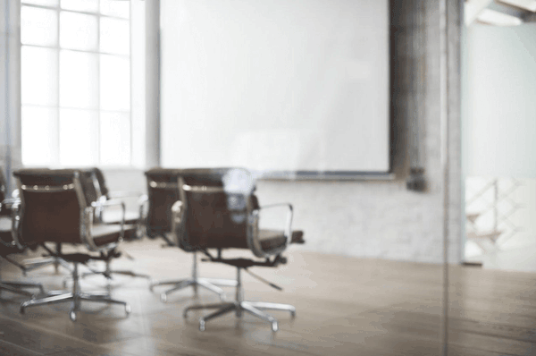 A room with rolling desk chairs and a screen on the wall