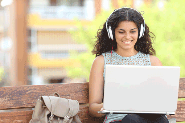 A Student using a laptop on a wooden bench