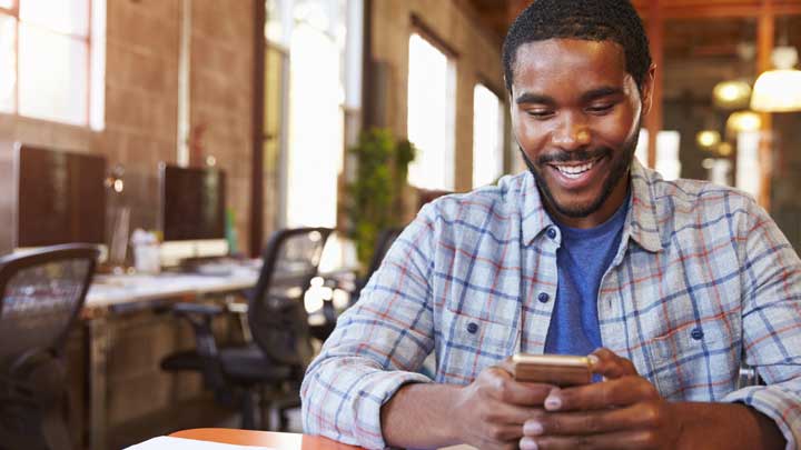 Smilende mand som bruger sin telefon