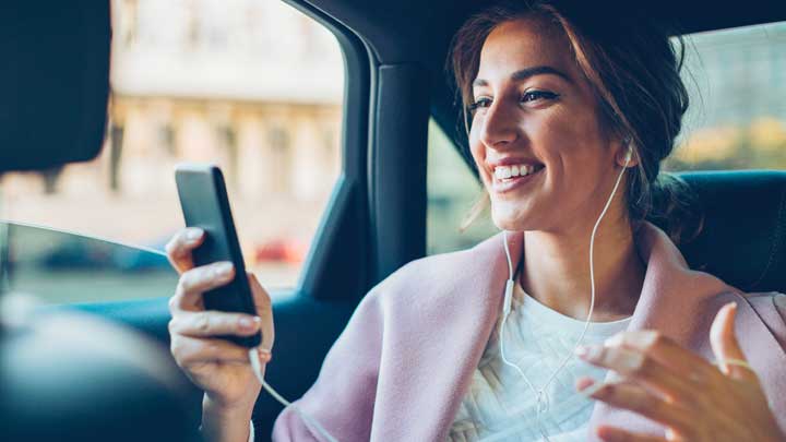 Mulher em um carro sorrindo usando seu telefone